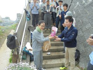 異動となった前区政推進課長の田中さんに1年半一緒に作業の汗を流した学生より感謝の花束贈呈